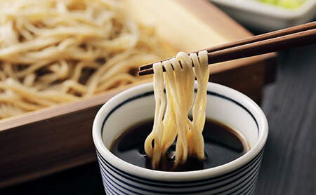 箸でつままれたつゆに浸る美味しそうな手打ちそば